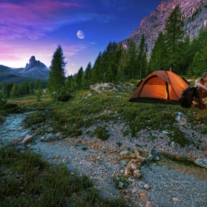 Mystical night landscape, in the foreground hike, campfire and tent